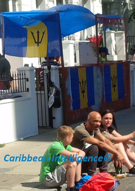 family sitting near stall with Barbados flags