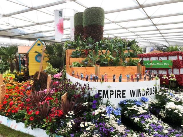 floral tribute of the Empire Windrush with Caribbean house and London bus